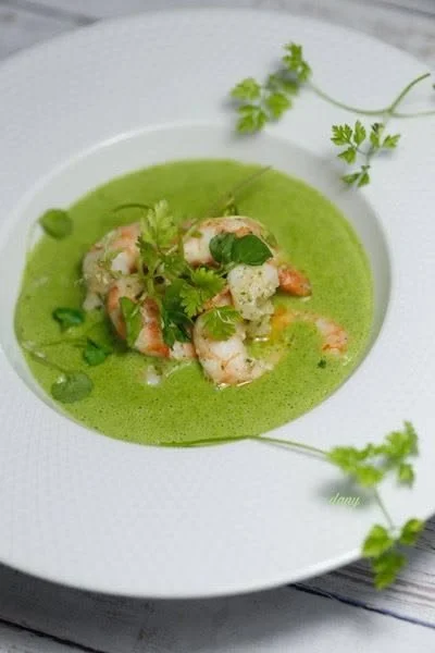 Crevettes aillées accompagnées de crème de cresson au parmesan dans une assiette