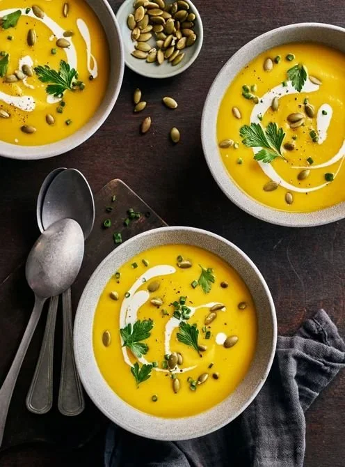 Potage à la citrouille crémeux servi avec des herbes aromatiques