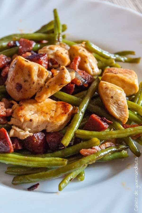 Poulet sauté aux haricots verts et chorizo servi dans une assiette
