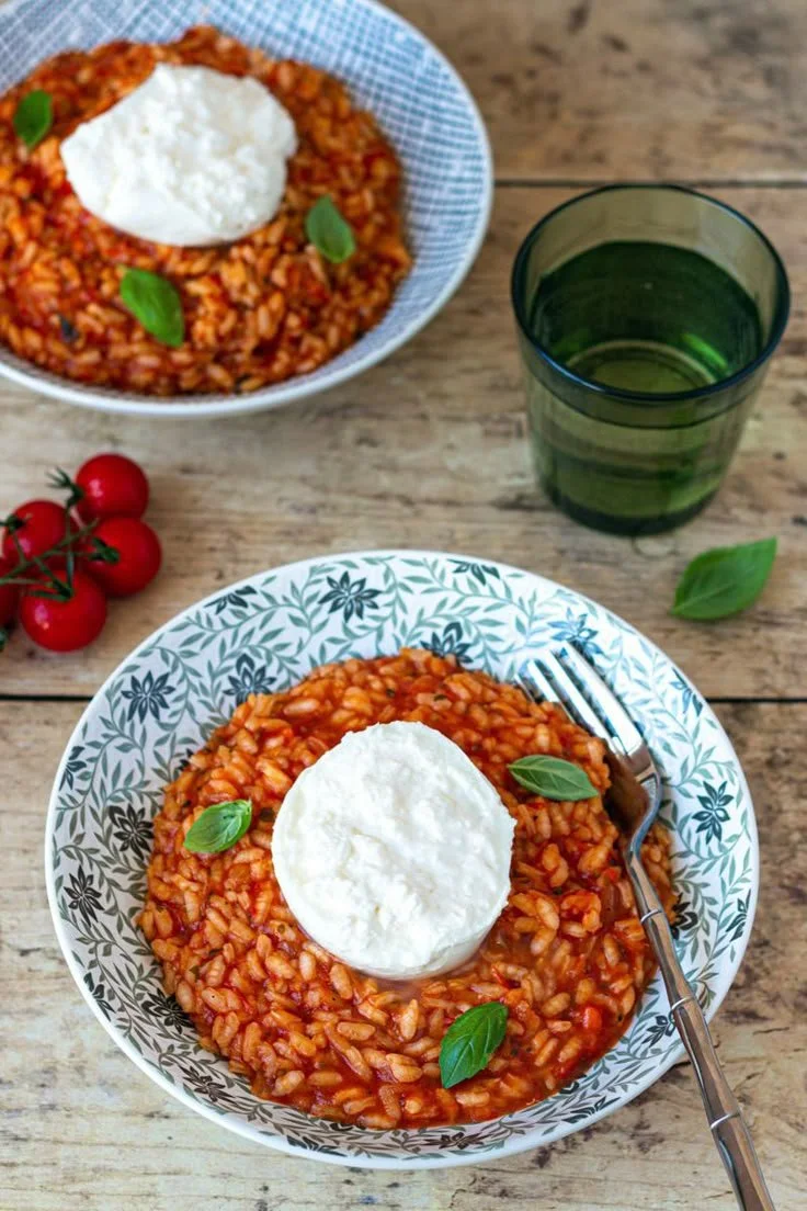 Risotto à la tomate, basilic et burrata présenté dans une assiette élégante.