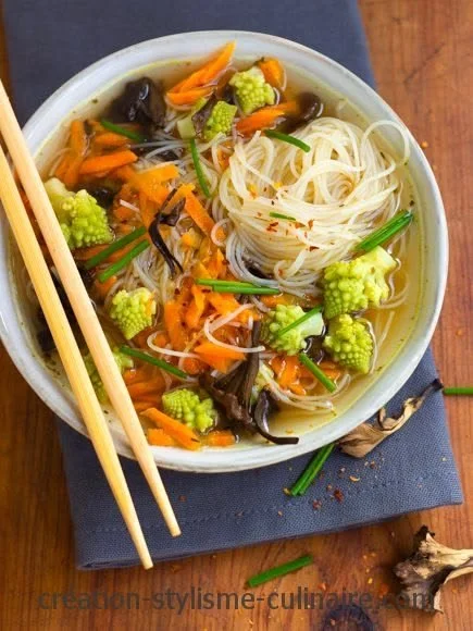 Soupe chinoise aux vermicelles de riz dans un bol, garnie d'herbes fraîches