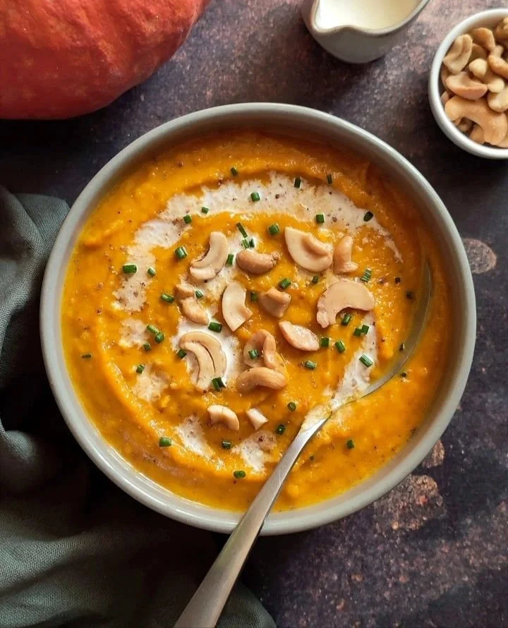 Bol de velouté potimarron servi avec des croûtons et des herbes fraîches